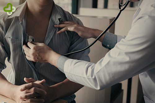 Врач слушает сердце мужчины с помощью фонендоскопа